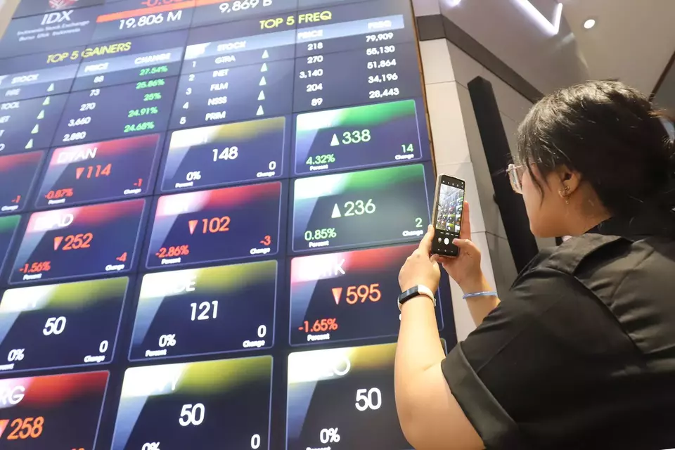 Pengunjung memotret layar pergerakan saham di gedung BEI, Jakarta. (Investor Daily/David Gita Roza)