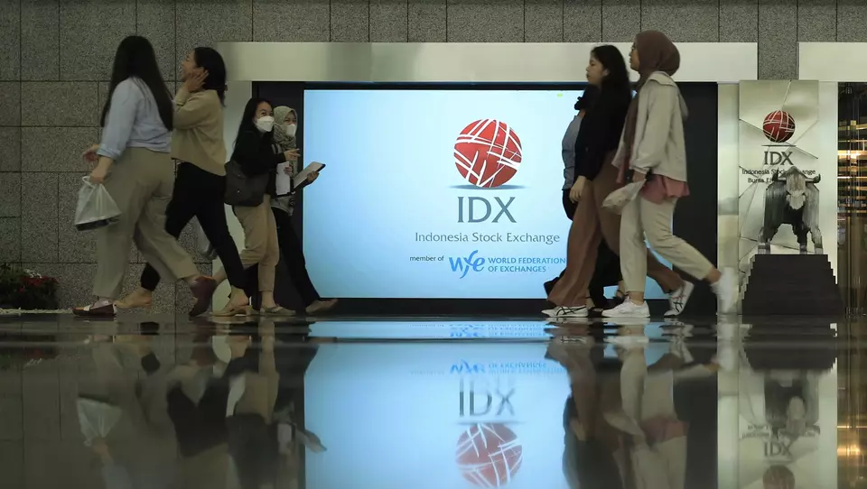 Pekerja melintasi layar penunjuk pergerakan saham di gedung BEI, Jakarta. (Investor Daily/David Gita Roza)