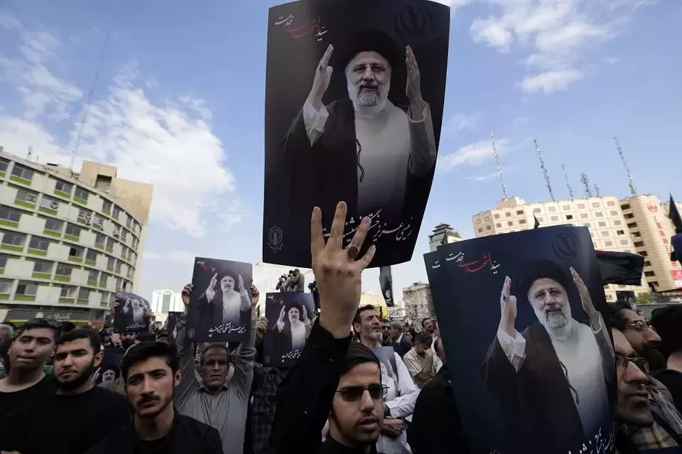 Warga Iran memegang poster Presiden Iran Ebrahim Raisi saat upacara berkabung untuknya di alun-alun Vali-e-Asr di pusat kota Teheran, Iran pada Senin (20/5/2024). (Foto: AP/Vahid Salemi)