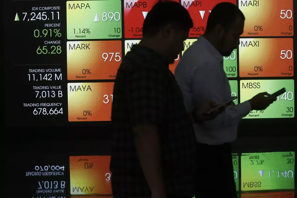 Pekerja melintasi layar pergerakan saham di gedung BEI, Jakarta. (Investor Daily/David Gita Roza)