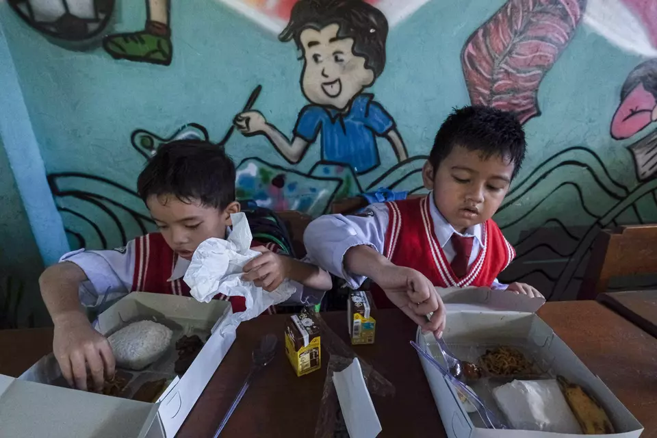 Dua murid SD menyantap makanan bergizi gratis di SDN 1 Kendari, Sulawesi Tenggara, belum lama ini. (ANTARA FOTO/Andry Denisah)