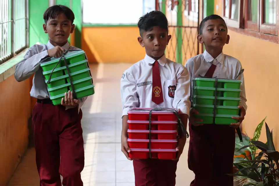 Pelajar membawa paket makanan pada pelaksanaan program Makan Bergizi Gratis (MBG) hari pertama di SD Negeri 56 Banda Aceh, Aceh, baru-baru ini. (ANTARA FOTO/Irwansyah Putra)