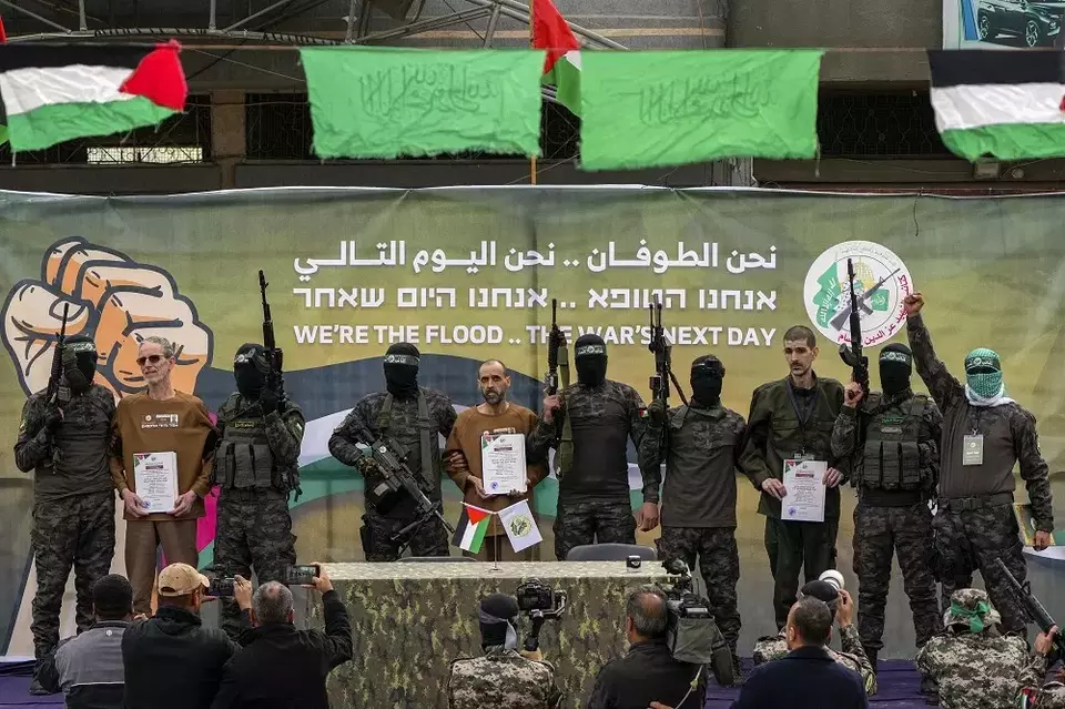 Tawanan Israel (dari kiri ke kanan) Ohad Ben Ami, Eli Sharabi, dan Or Levy yang disandera oleh Hamas di Gaza sejak 7 Oktober 2023 dikawal oleh pejuang Hamas sebelum diserahkan ke Palang Merah di Deir al-Balah, Jalur Gaza tengah, Sabtu (8/2/2/2025). (Foto: AP/Abdel Kareem Hana)
