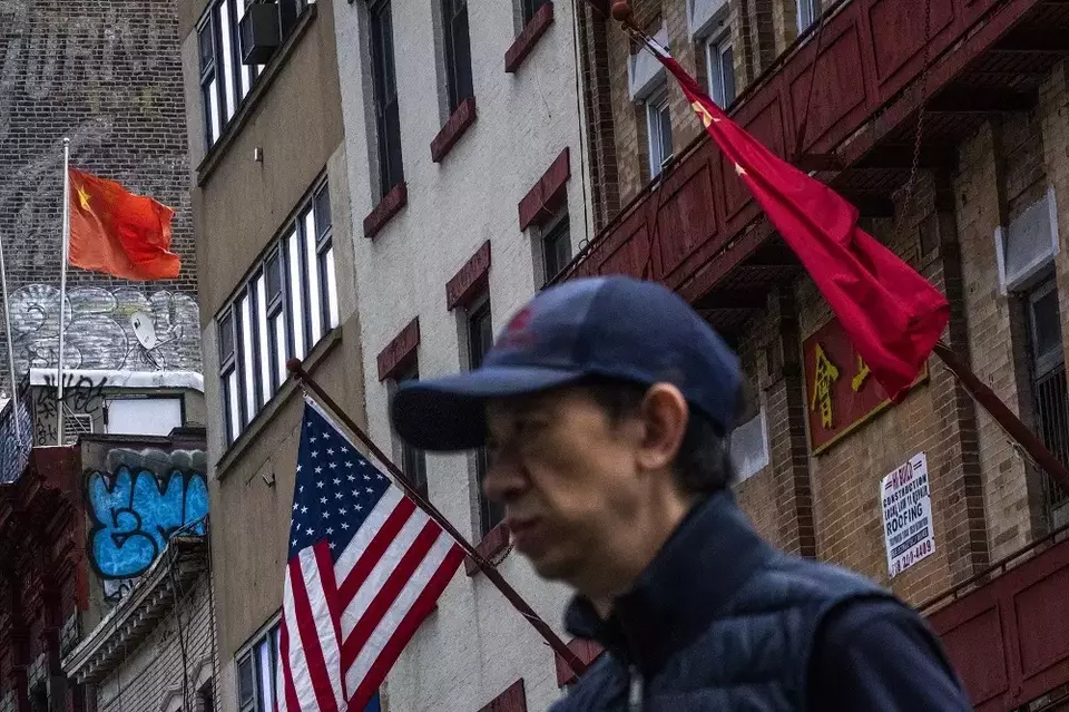 Bendera nasional AS dan China berkibar saat seseorang lewat di kawasan Pecinan di New York, Selasa (8/4/2025). (Foto: AP/ Eduardo Munoz Alvarez)