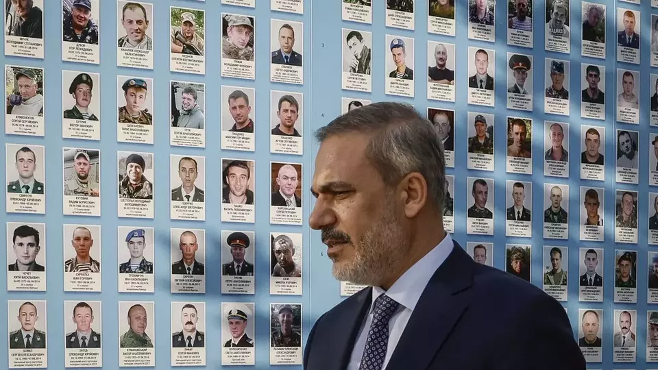 Menteri Luar Negeri (Menlu) Turki Hakan Fidan melihat foto-foto prajurit yang gugur setelah upacara peletakan bunga di tembok peringatan di Kyiv, Ukraina, Jumat (30/5/2025). (Foto: AP/ Efrem Lukatsky)