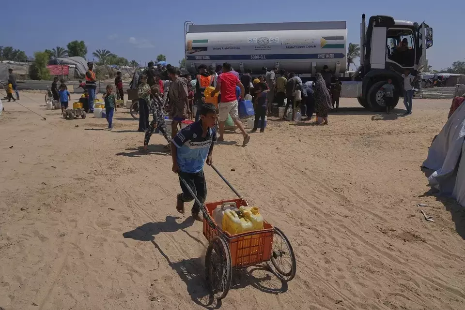 Seorang anak laki-laki Palestina mendorong gerobak berisi jeriken air setelah mengambilnya di sebuah kamp pengungsi di Khan Younis, Jalur Gaza selatan, Sabtu (19/7/2025). (Foto: AP/ Abdel Kareem Hana)