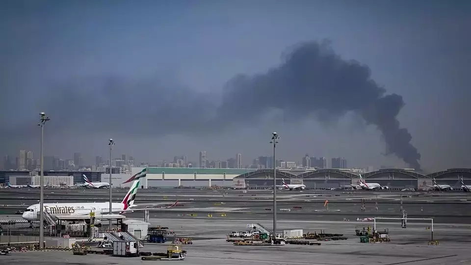 Kepulan asap yang disebabkan oleh serangan Iran terlihat di latar belakang saat pesawat-pesawat Emirates diparkir di Bandara Internasional Dubai setelah penutupannya di Dubai, Uni Emirat Arab, Minggu (1/3/2026). (Foto: AP/ Altaf Qadri)