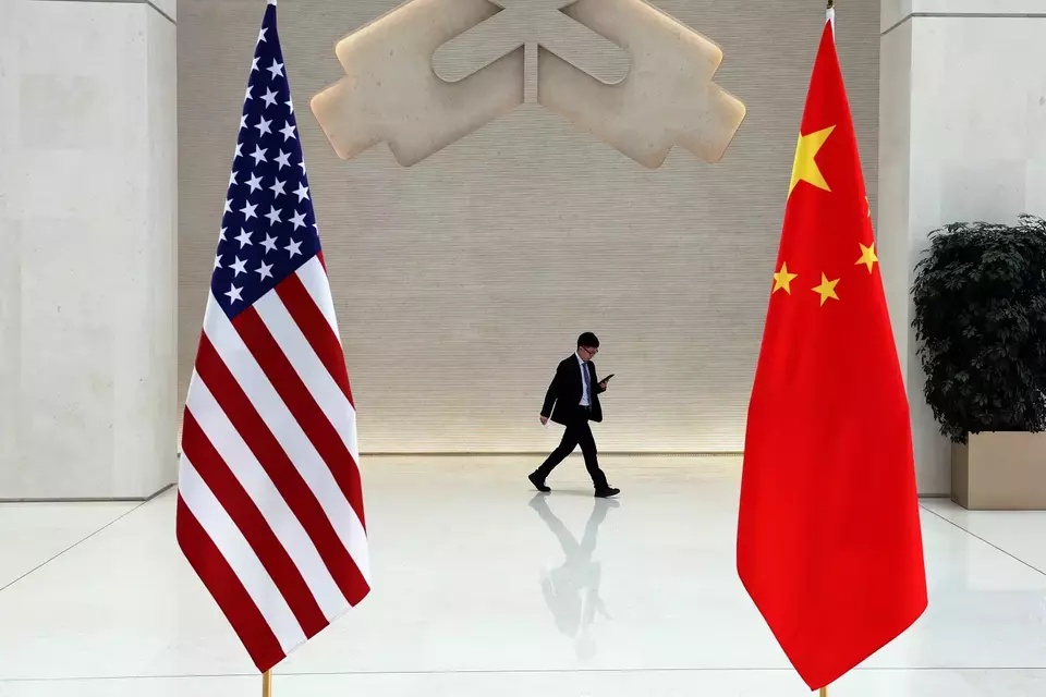 Seorang pria berjalan melewati bendera AS dan China pada hari pertemuan antara Menteri Keuangan AS Janet Yellen dan Gubernur Bank Rakyat China (PBoC) Pan Gongsheng, Beijing, China.