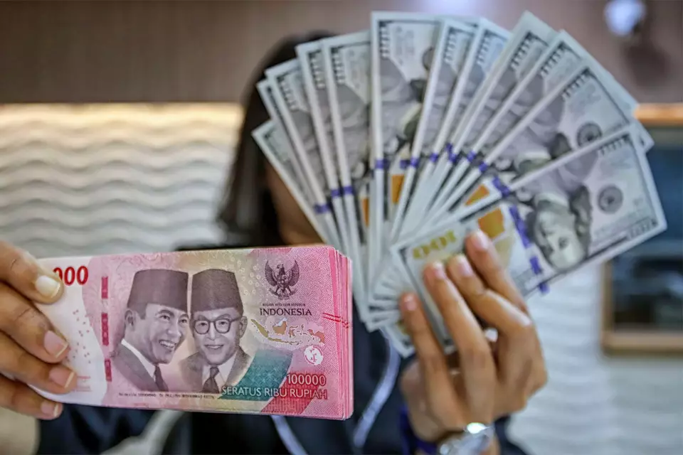 Petugas kasir menunjukkan uang pecahan dolar Amerika Serikat (AS) di gerai penukaran mata uang asing Ayu Masagung, Jakarta Pusat, Selasa (12/5/2026). (B-Universe Photo/Joanito De Saojoao)
