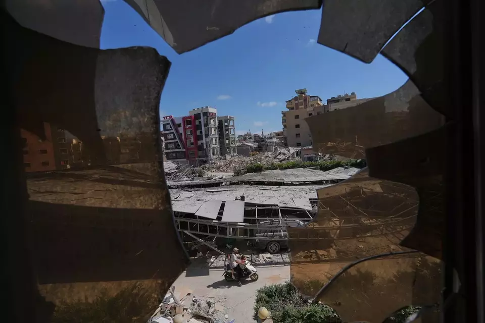 Bangunan-bangunan yang rusak akibat serangan Israel terlihat melalui pecahan kaca dari Rumah Sakit Jabal Amel di kota pelabuhan Tyre, Lebanon selatan pada Kamis (18/6/2026). (Foto: AP/ Hassan Ammar)