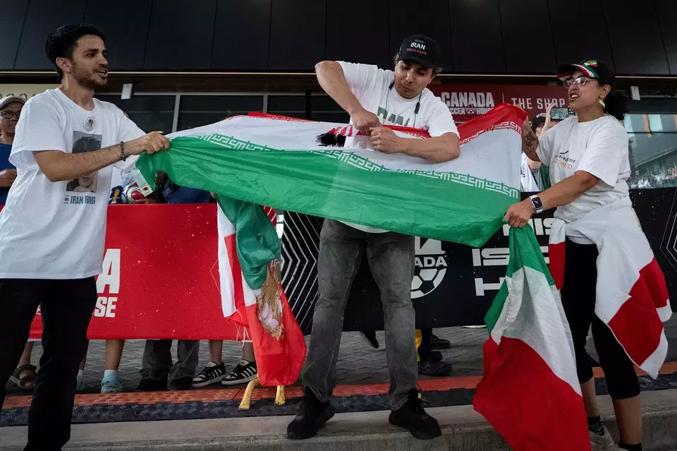 Seorang pria merobek bendera Iran saat acara nonton bareng pertandingan Piala Dunia FIFA antara Iran dan Selandia Baru, di North Vancouver, British Columbia, Senin (15/6/2026). (Foto: Ethan Cairns/ The Canadian Press via AP)