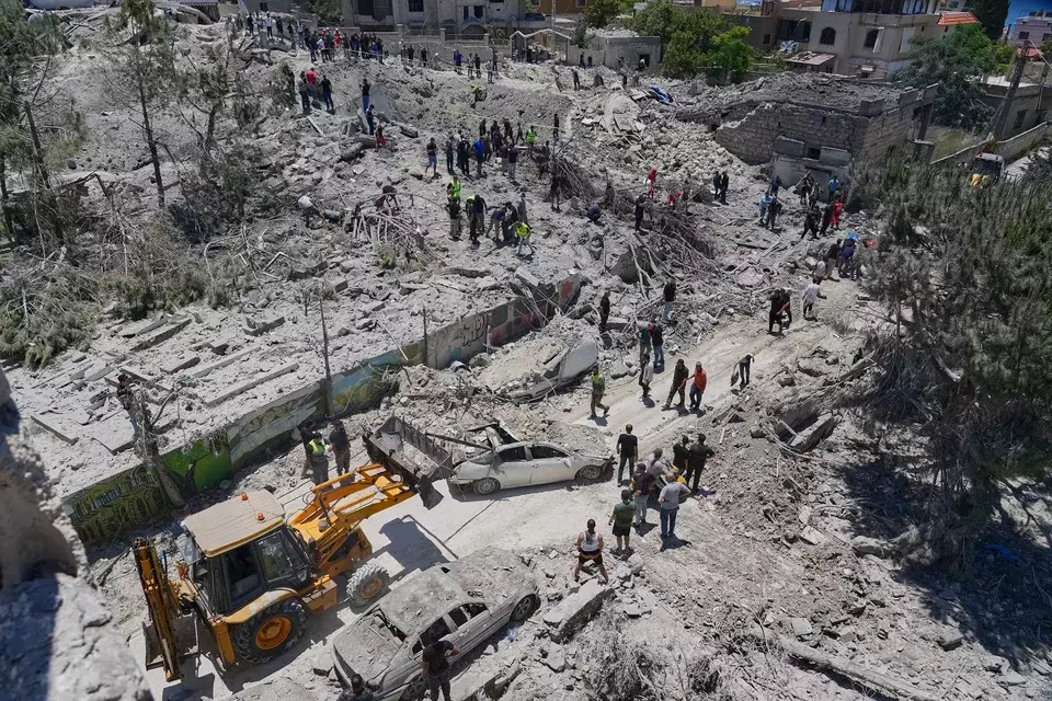 Petugas penyelamat dan warga mencari korban di bangunan yang hancur akibat serangan udara Israel di desa Qannarit, Lebanon selatan, Sabtu (20/6/2026). (Foto: AP/ Mohammed Zaatari)