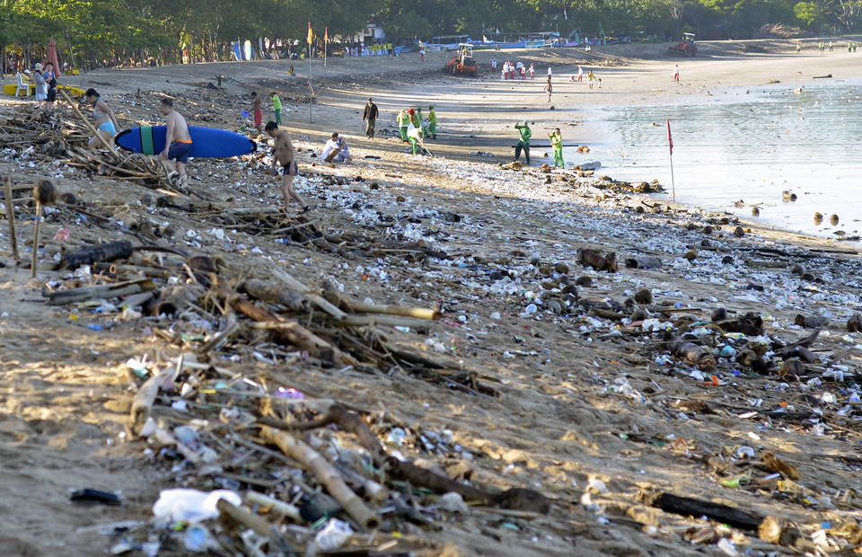 Tourists walk among trash washed ashore by strong currents at Kuta Beach in Bali on Feb. 15, 2017. (Antara Photo/Wira Suryantala)