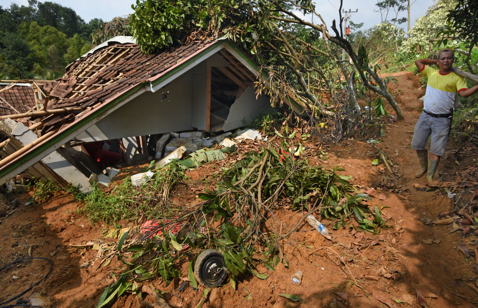 A man walks past a house damaged by a landslide in Lebak, West Java, last year. (Antara Photo/Asep Fathulrahman)