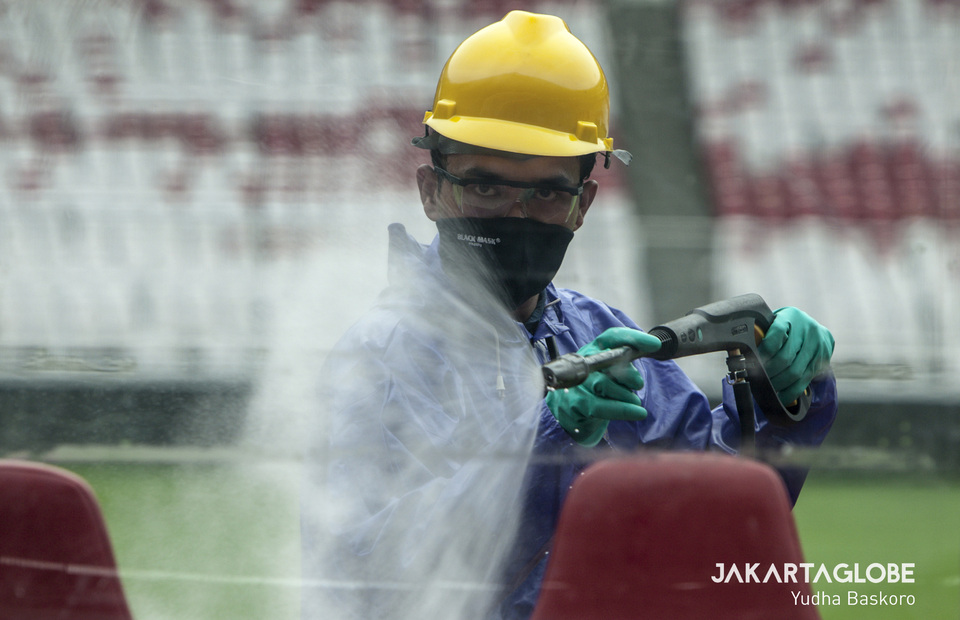 A medical workers sprays benches inside the Gelora Bung Karno Stadium with disinfectant. (JG Photo/Yudha Baskoro)