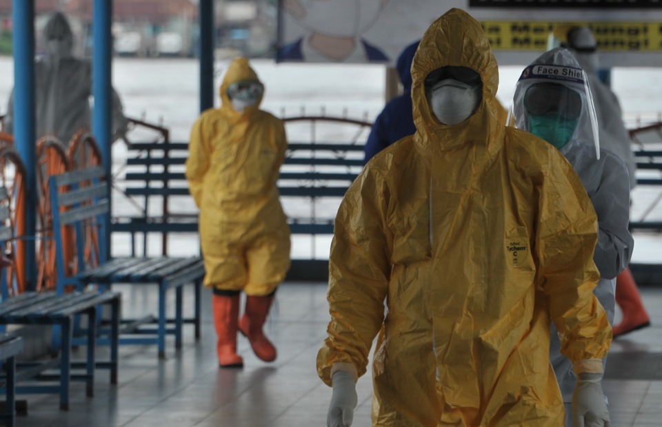 Medical workers wait for the Marina 1626 tugboat to dock in Palembang, South Sumatra, on Thursday. Some of the crew workers on the boat are thought to have contracted Covid-19. (Antara Photo/Feny Selly)