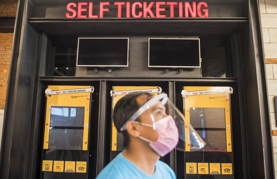 An employee wears mask and face shield when inspecting ticket machine at a CGV Cinemas' movie theater in Bandung, West Java, in July. (Antara Photo/M. Agung Rajasa)