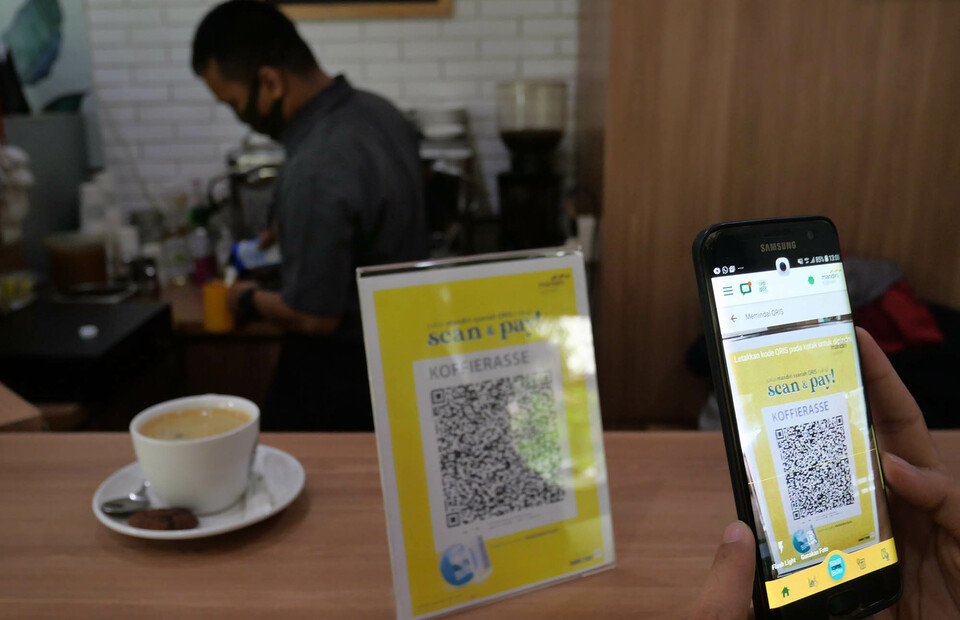 A shopper scans a quick response code Indonesian standard (QRIS) to pay for a cup of coffee in a cafe in Jakarta last July. (ID Photo/David Gita Roza)