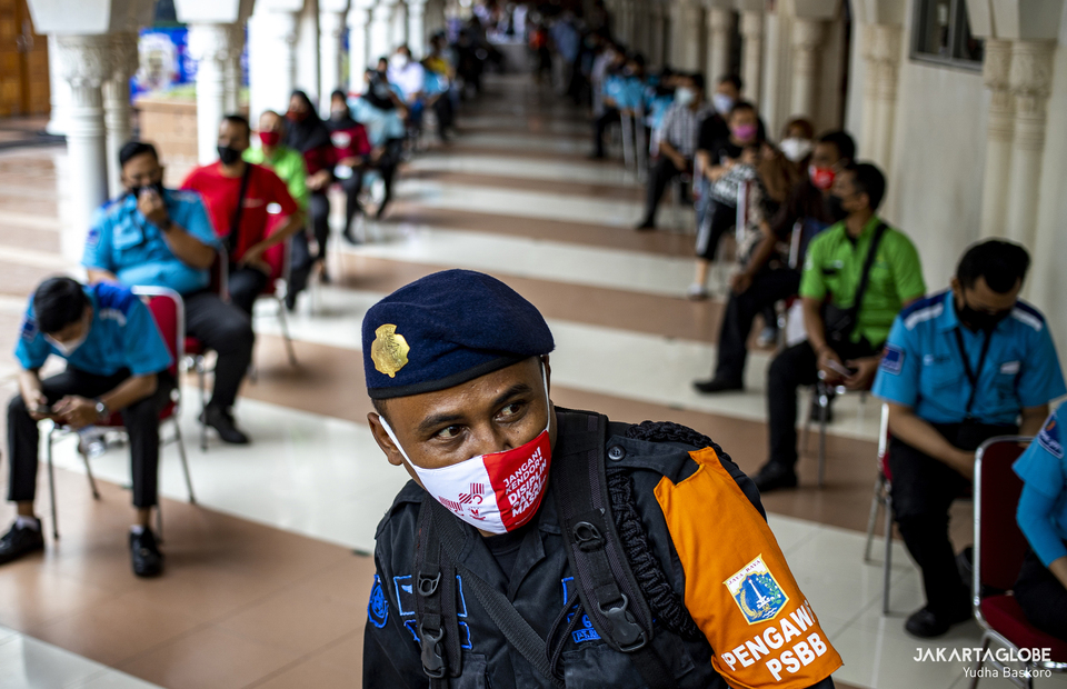 Indonesian police personnel stands in front of a line of traders during second phase of COVID-19 mass vaccination in Tanah Abang market, Central Jakarta on Feb 17, 2021. (JG Photo/Yudha Baskoro)