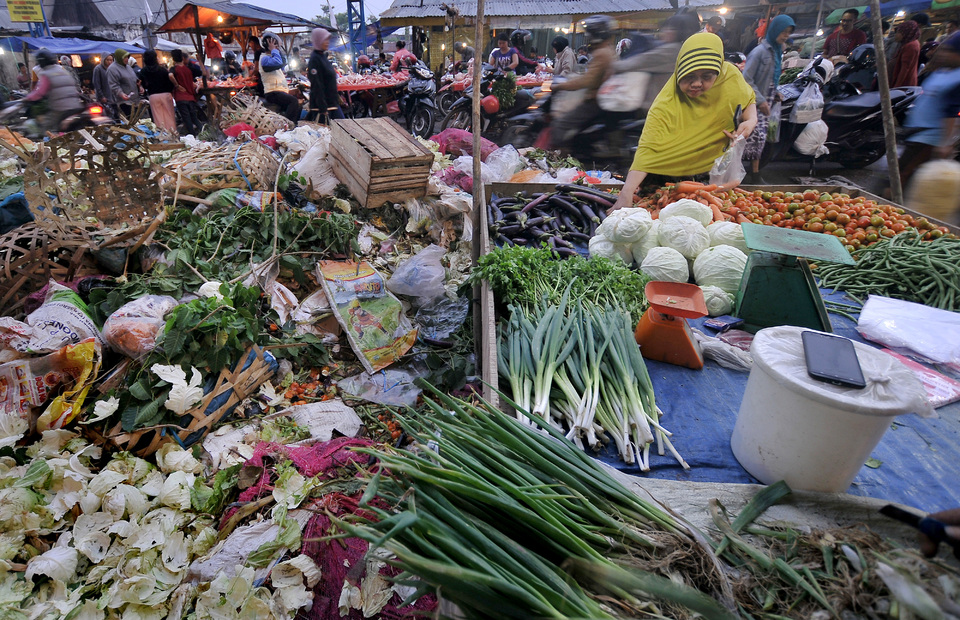 This 2017 file photo shows a woman picks some vegetables to purchase from a stall next to a pile of food garbage at Angso Duo traditional market in Jambi. (Antara Photo/Wahdi Septiawan)