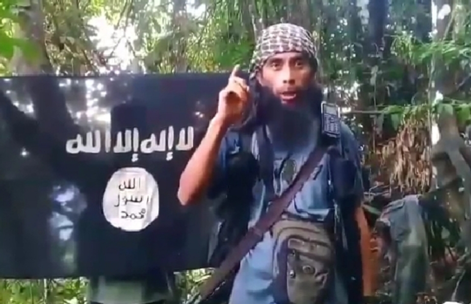 A screen capture from a video shows purported Ali Kalora speaks in front of an ISIS flag. (Videography)