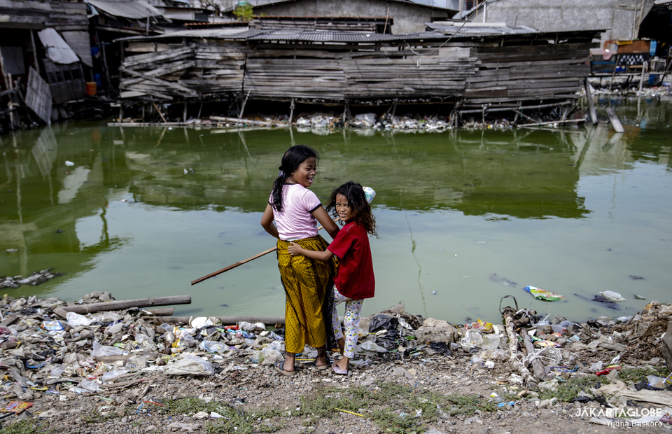Two girls play by a polluted waterway in Cilincing, North Jakarta on June 23, 2022. (JG Photo/Yudha Baskoro)
