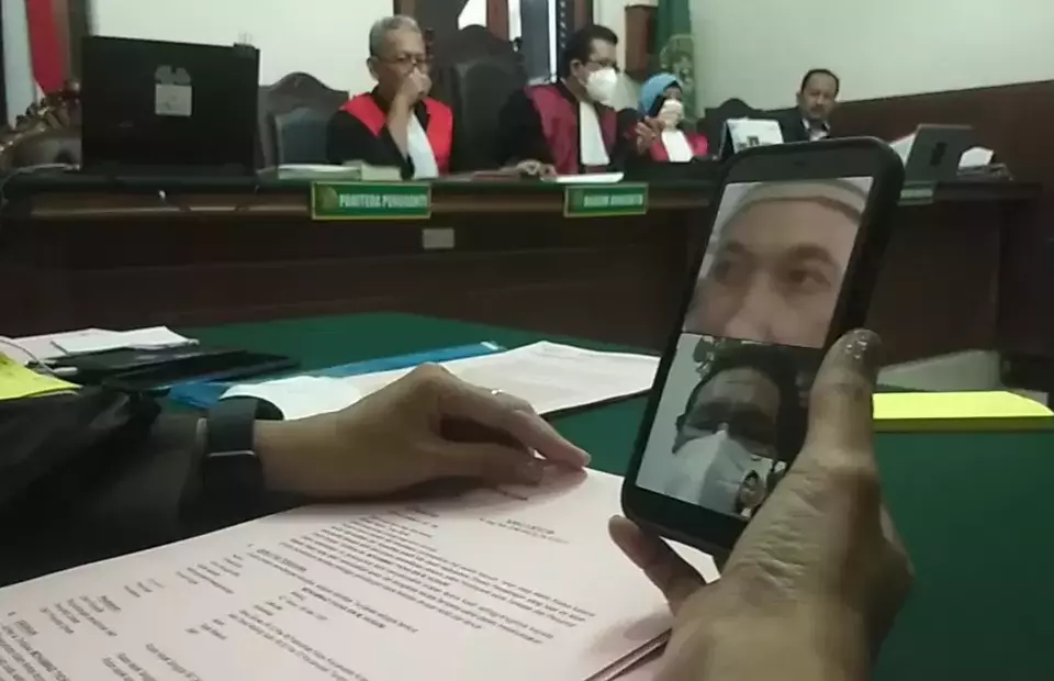 A prosecutor holds a mobile phone during a sentencing demand hearing at the Surabaya District Court against two men accused of stealing money from a BCA account on January 30, 2022. Both defendants follow the hearing virtually. (B-Universe photo/Agung Dharma)