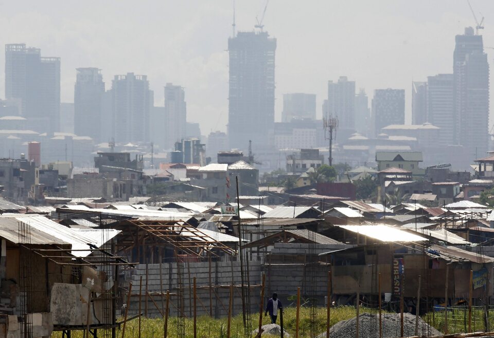 A file photo dated May 15, 2014 showing a Filipino informal settler walking along shanties with a backdrop of Makati’s financial district in Taguig city, south of Manila, Philippines. (EPA Photo/Francis R. Malasig)