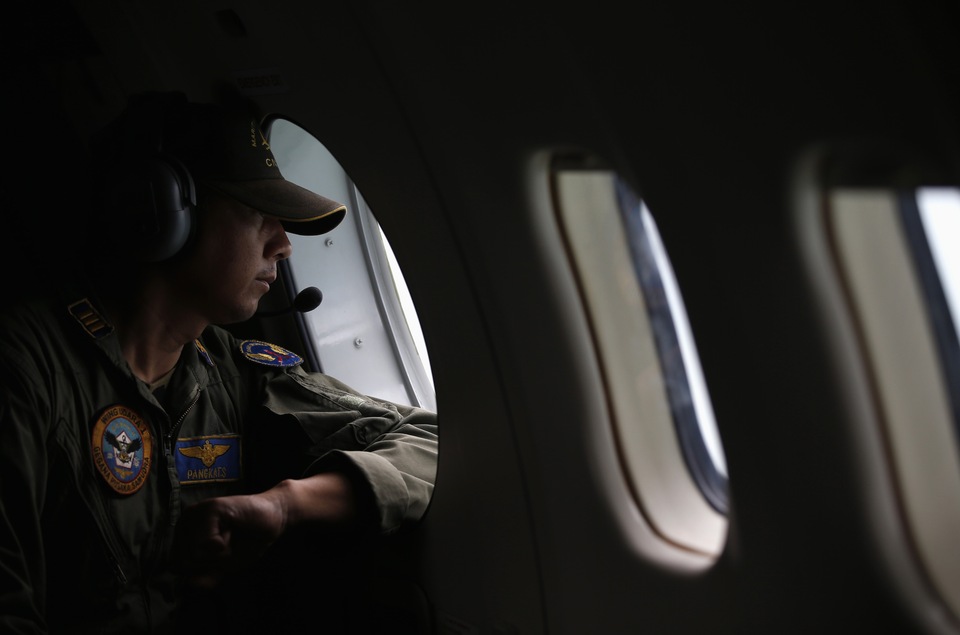 A crew member from an Indonesian Navy maritime surveillance plane looks out a window during a search for wreckage and the remains of passengers on board Indonesia AirAsia flight QZ850, over the Karimata Strait south of Pangkalan Bun, Central Kalimantan, on Jan. 1, 2015. (Reuters Photo/Darren Whiteside)