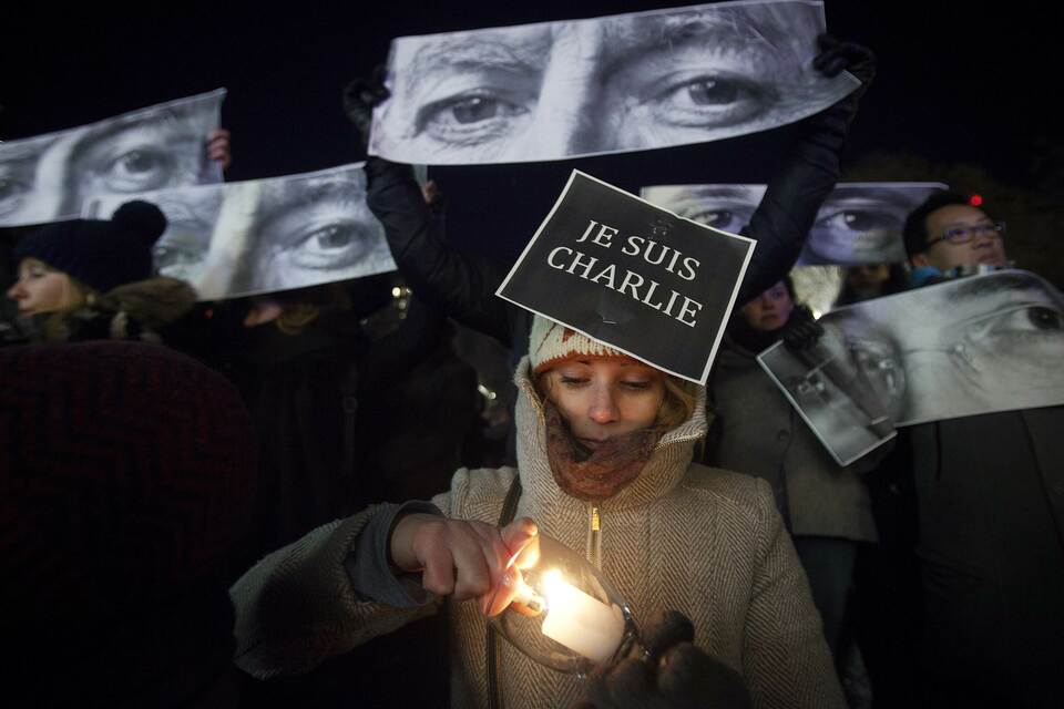Amandine Marbach from Strasbourg, France, lights a candle as she takes part in a vigil to pay tribute to the victims of a shooting, by gunmen at the offices of weekly satirical magazine Charlie Hebdo in Paris, in the Manhattan borough of New York on Jan. 7, 2015. (Reuters Photo/Carlo Allegri)