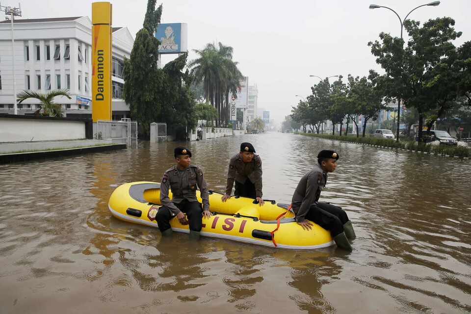 Policemen rest on an inflatable raft in the flooded Kelapa Gading area of North Jakarta on Jan. 23, 2015. Flooding has become an increasingly severe threat to residents of the capital over the years. (Reuters Photo/Beawiharta)