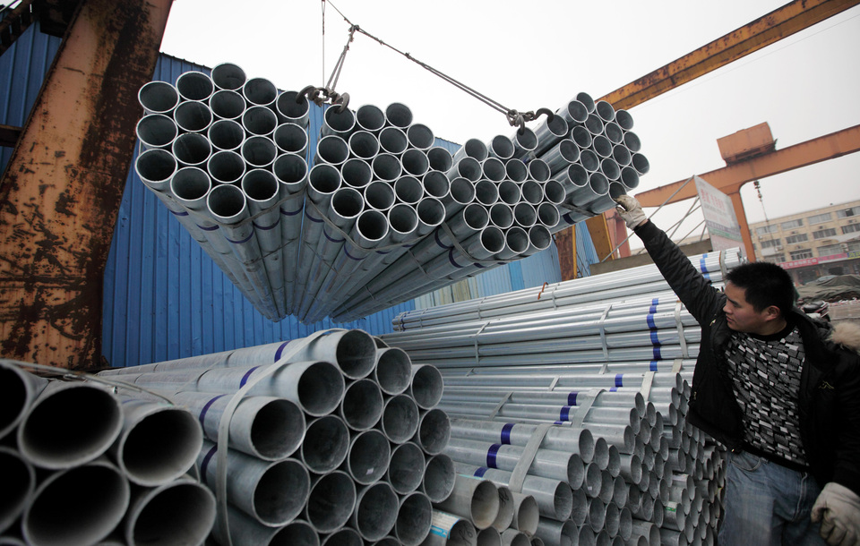 A worker assists to lord steel pipes onto a truck at a storage yard of a trading firm in Shanghai, China, on Friday, Feb. 1, 2013.  (Bloomberg Photo/Tomohiro Ohsumi)