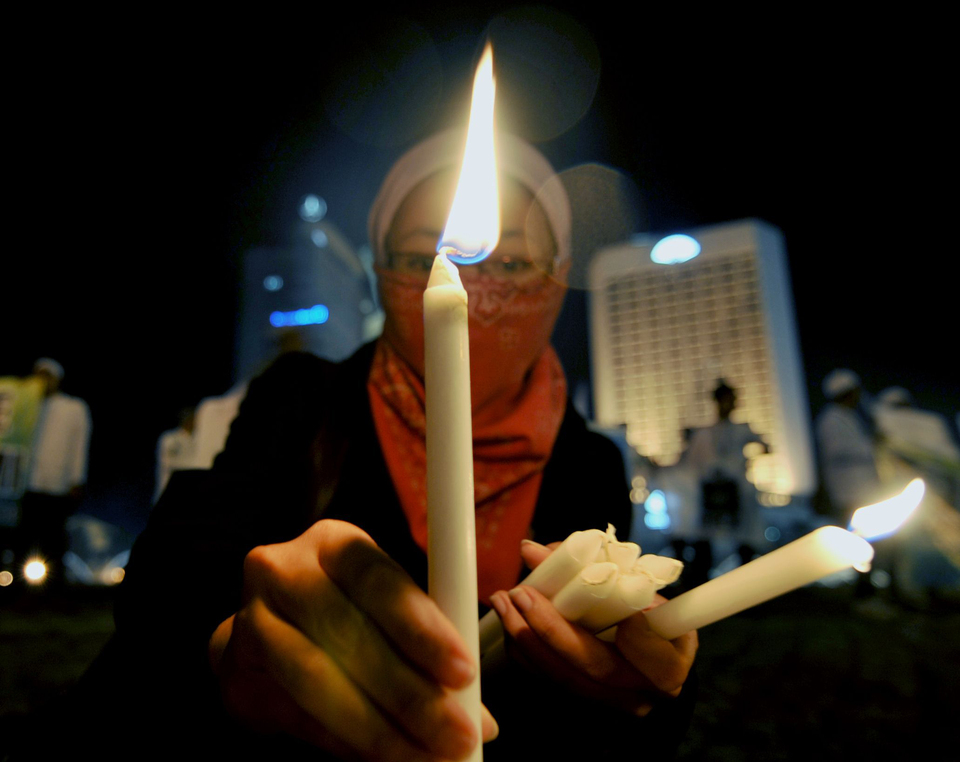 An Indonesian Muslim woman with hijab holds a candle as part of a rally for peace in Jakarta. (AFP Photo/Bay Ismoyo)