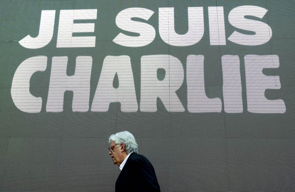 The renowned Argentinian cartoonist and illustrator Hermenegildo Sabat walks next to a big screen reading ‘Je suis Charlie’ (I am Charlie) during a tribute to the victims in the offices of the satirical weekly Charlie Hebdo in Paris, outside the ‘Museo del Humor,  in Buenos Aires, on Jan. 13, 2015. (AFP Photo/Alejandro Pagni)