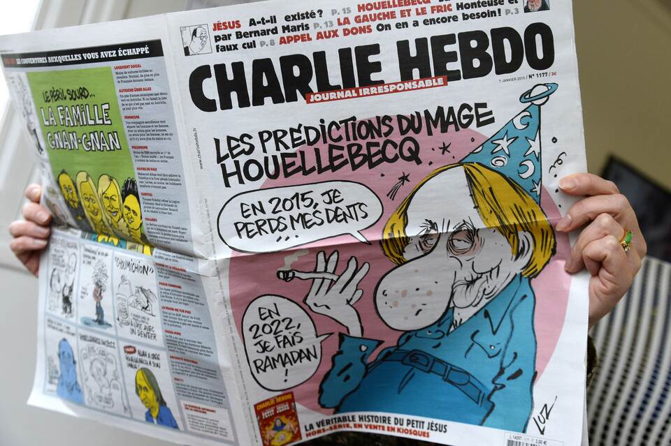 A person reads the latest issue of the French satirical newspaper Charlie Hebdo in Paris on Jan. 7, 2015, after gunmen armed with Kalashnikovs and a rocket-launcher opened fire in the offices of the weekly in Paris, killing at least 12. (AFP Photo/Bertrand Guay) 