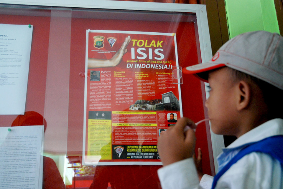 A child views a poster hanging in a government office in Depok, West Java, says ‘Reject the Islamic State of Iraq and Syria (ISIS)’. (Antara Photo/Indrianto Eko Suwarso)
