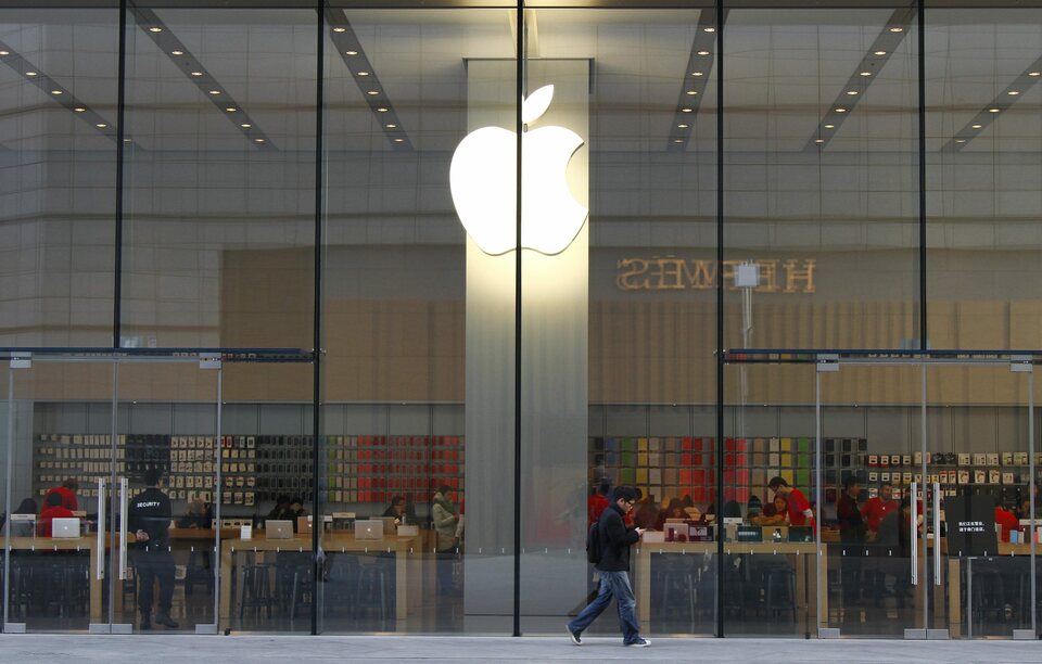 A man looking at his smartphone walks past an Apple Store in Beijing, on Jan. 28, 2015. (EPA Photo/Rolex Dela Pena)