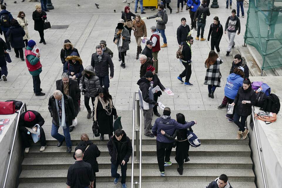 Young people hand out advertising leaflets to passersby in Athens on Feb. 12, 2015. (AFP Photo/Louisa Gouliamaki)
