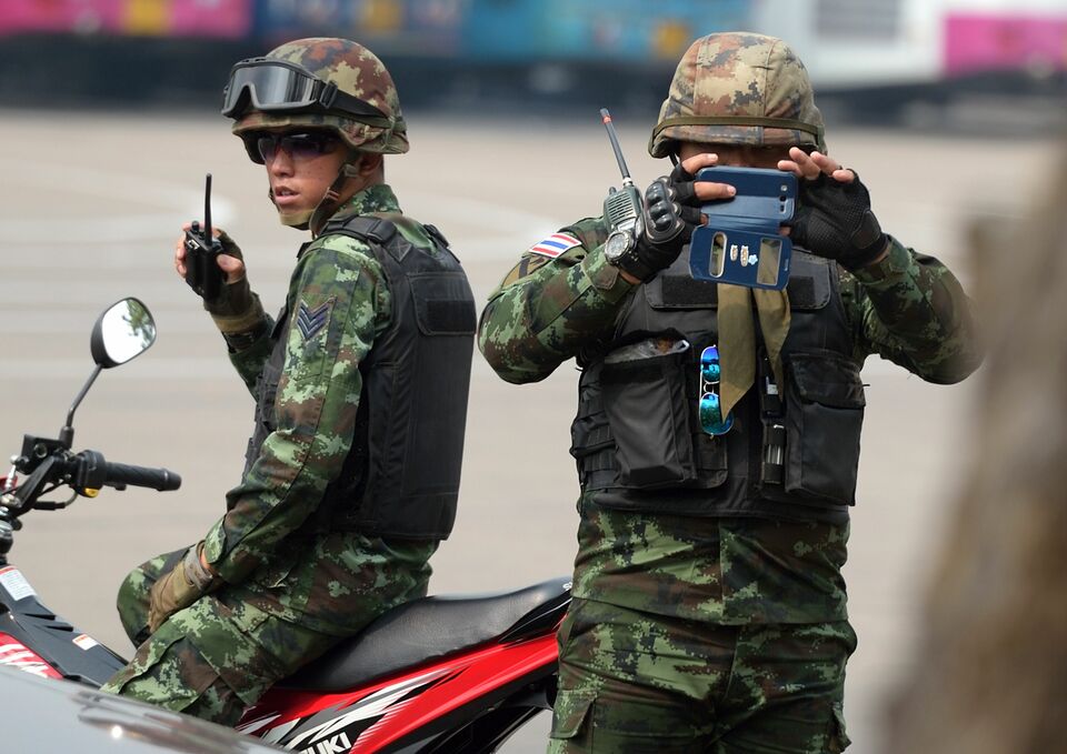A Thai soldier takes a picture of members of the media as they stand guard during a visit by Chaturon Chaisang, a former education minister, at an army base in Bangkok on Thursday. Chaturon is one of two former ministers from the ousted government of ex-premier Yingluck Shinawatra summoned by the military, which is escalating its campaign to crush dissent since seizing power last May. (AFP Photo/Pornchai Kittiwongsakul)