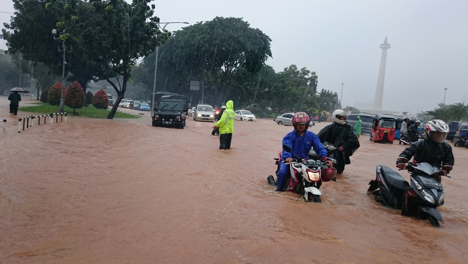 Motorists pass a flooded street in front of the presidential palace in Jakarta on Monday. (Antara Photo/Fanny Octavianus)