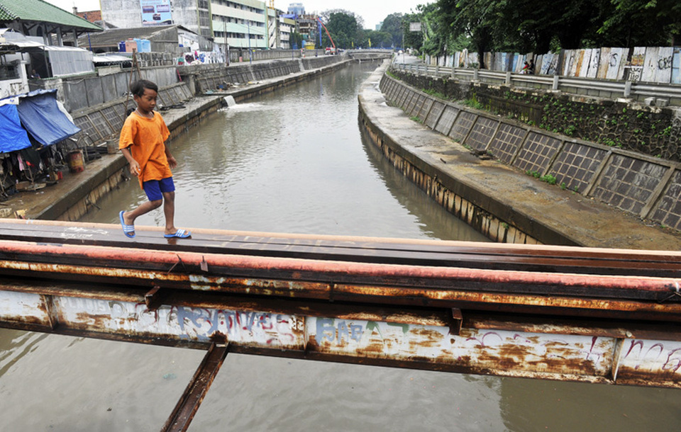 A boy crosses a utility beam over the Ciliwung River in Kramat, Central Jakarta, on Feb. 19, 2015. (Antara Photo/Andika Wahyu)