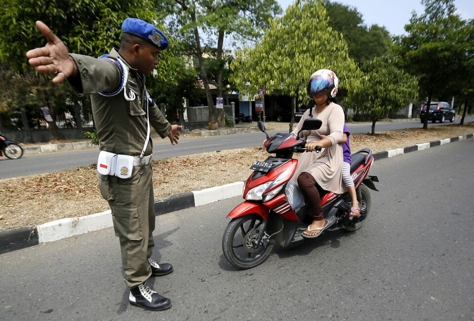 A sharia policeman stops a motorcyclist for wearing tight jeans during a sharia police raid in Banda Aceh on March  24, 2014. Neighboring North Aceh district has passed a bylaw segregating men and women in all public spaces.  (EPA Photo/Hotli Simanjuntak) 