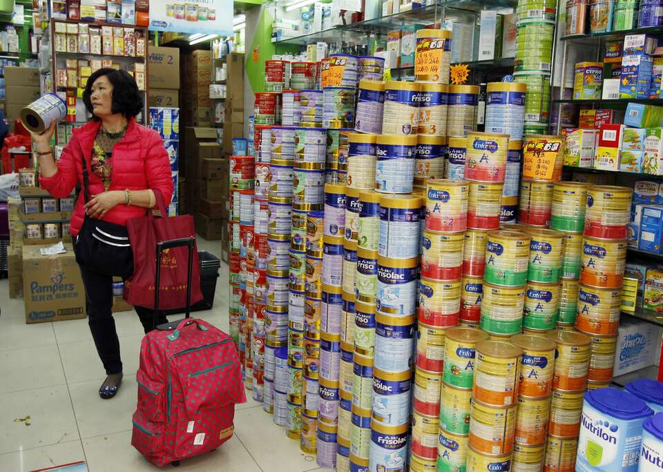 A Chinese visitor asks for the price of a canned infant formula at a store, in Hong Kong February 9, 2015. (Reuters Photo/Liau Chung-ren)