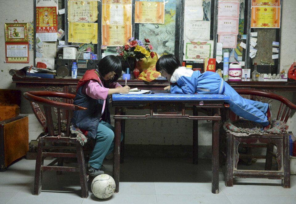 A student of Sunji Township Centre Primary School steps on a soccer ball as she does her homework at her home in Sunji township of Shanghe county, Shandong province March 24, 2015.(Reuters Photo/Stringer)