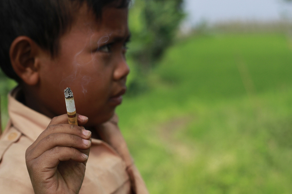 Dihan smoking near his house. The Garut, West java, native smokes up to three packs of cigarettes a day.  (JG Photo/Rezza Estily)
