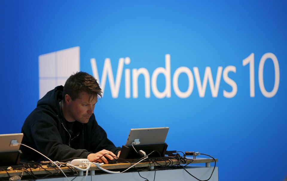 A man works on a laptop computer near a Windows 10 display at Microsoft Build in San Francisco, California April 29, 2015. (Reuters Photo/Robert Galbraith)