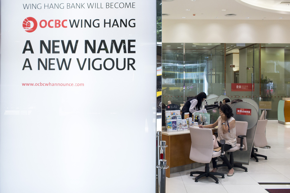 A sign reads 'Wing Hang Bank Will Become OCBC Wing Hang, A New name, A New Vigour' outside a Wing Hang Bank Ltd. branch in Hong Kong, China, on Friday, Aug. 22, 2014. Oversea-Chinese Banking Corp., Southeast Asia’s second-largest lender by assets, plans to raise S$3.37 billion ($2.7 billion) by offering shares to existing holders after its acquisition of Hong Kong’s Wing Hang Bank Ltd. Photographer: Brent Lewin/Bloomberg