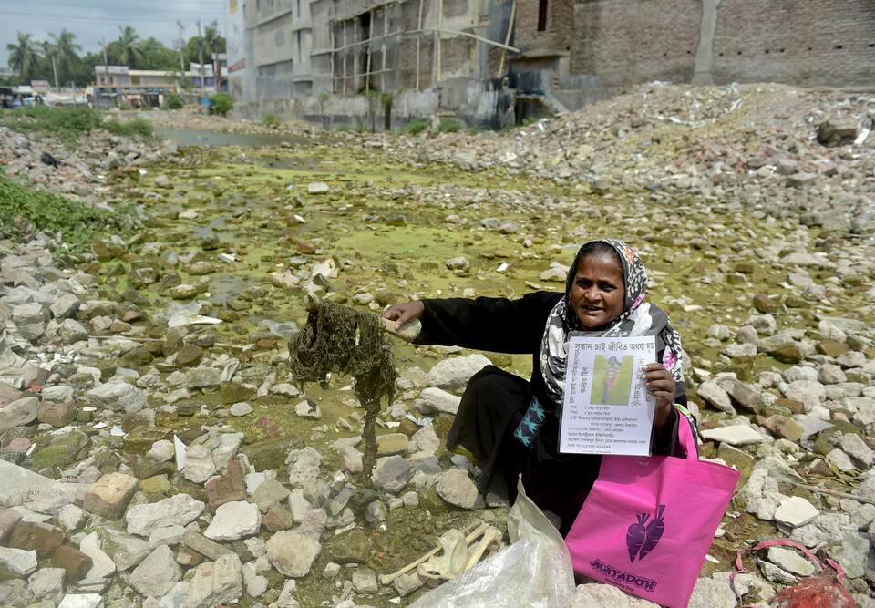 In this photograph taken on April 21, 2015, a Bangladeshi woman holds a laminated picture of a missing relative and a bone fragment on the site of the former Rana Plaza garment complex in Savar on the outskirts of Dhaka, almost two years after the disaster which saw more than 1,100 people dead in one of the world’s worst industrial disasters. (AFP Photo/Munir uz Zaman)