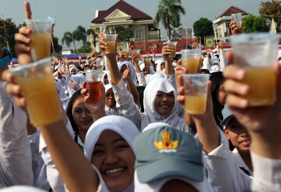 Some of thousands students raise their glasses as they attend drink ‘Jamu’ (herbal drinks) together at Sukoharjo district, Solo, Central Java, April 1, 2015. The ceremony of drinking jamu together follows by thousands students as a campaign to promote Jamu as a healthy drinks for youth and mark the Sukoharjo as the Jamu district in  Indonesia. (JG Photo/Jurnasyanto Sukarno)