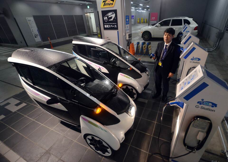 In this picture taken on April 7, 2015, an employee of parking operator 'Park 24' demonstrates how to charge Toyota's electric personal mobility vehicle i-Road in Tokyo. (AFP Photo/Yoshikazu Tsuno)